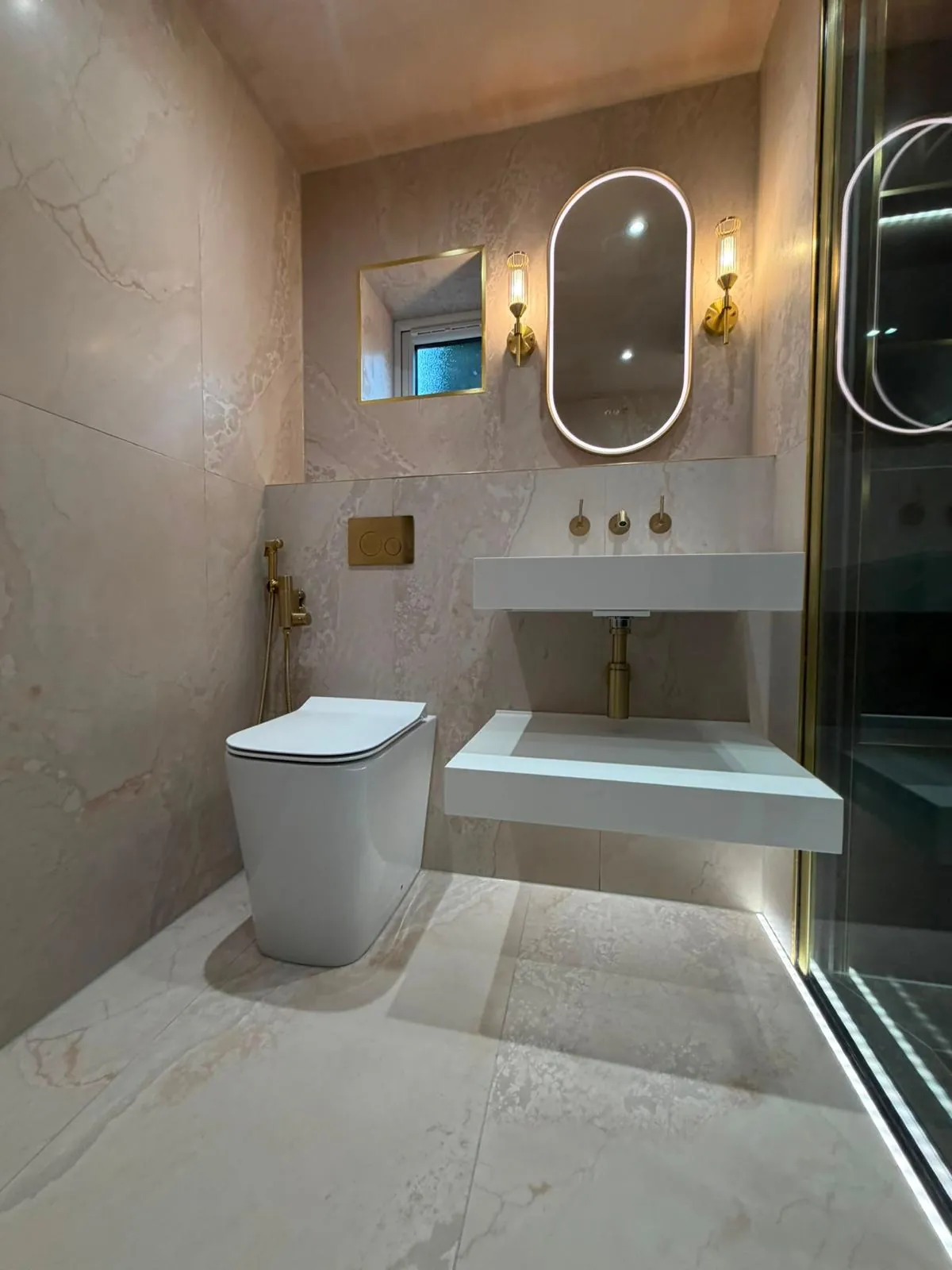 Blush and brass luxury en-suite with oval LED mirror and floating basin in Keighley